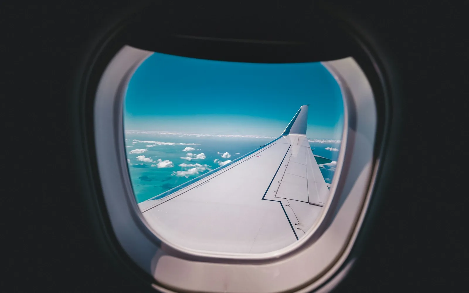 Aircraft wing above the clouds, seen from a passenger window
