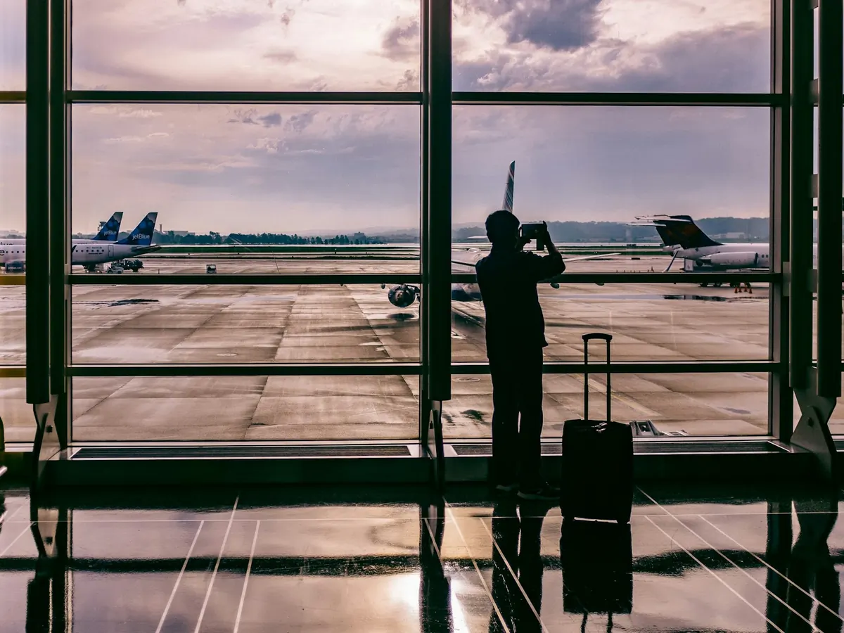 Traveller with luggage watching aircraft from a terminal window