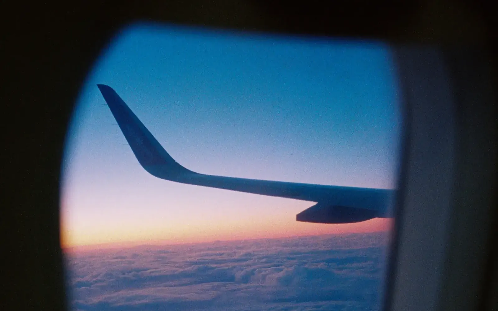 Airplane wing at sunset through a cabin window