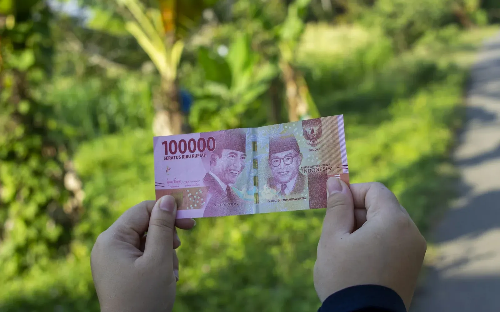 Hand holding an Indonesian 100,000 rupiah banknote