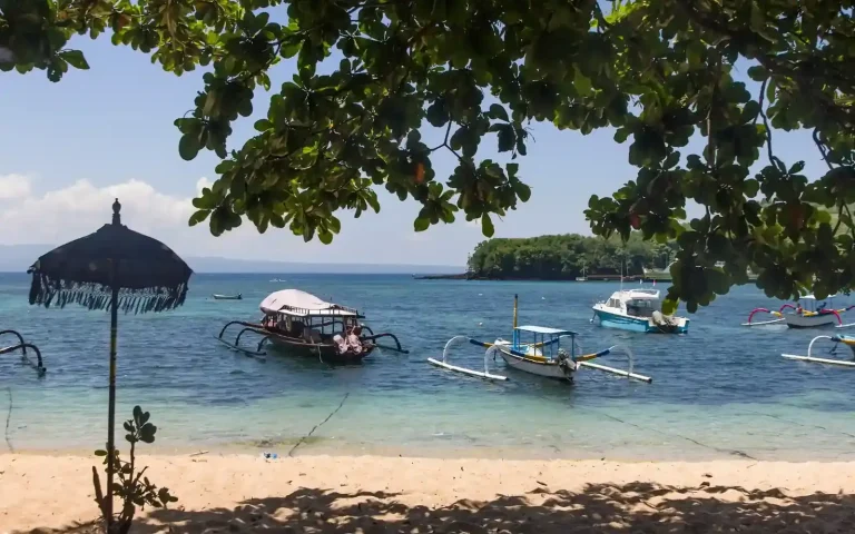 Traditional jukung boats and a beach umbrella at Padang Bai