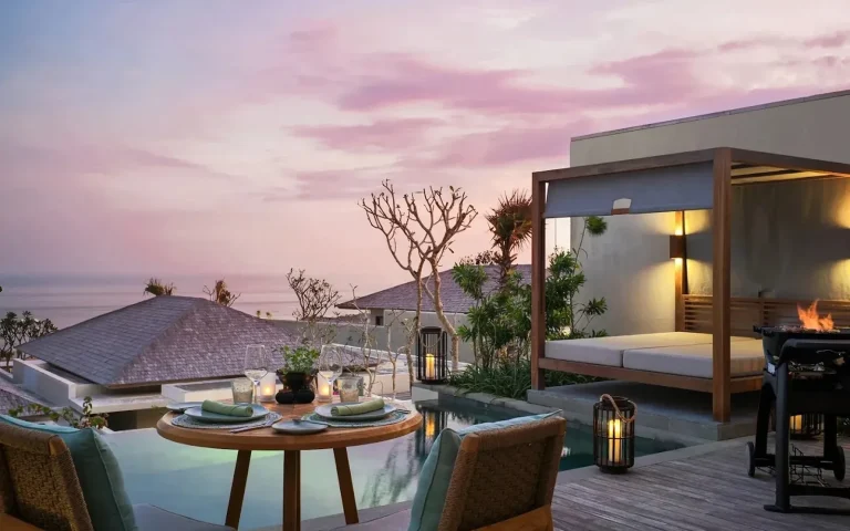Villa terrace at dusk with a pool and daybed overlooking the sea in Uluwatu